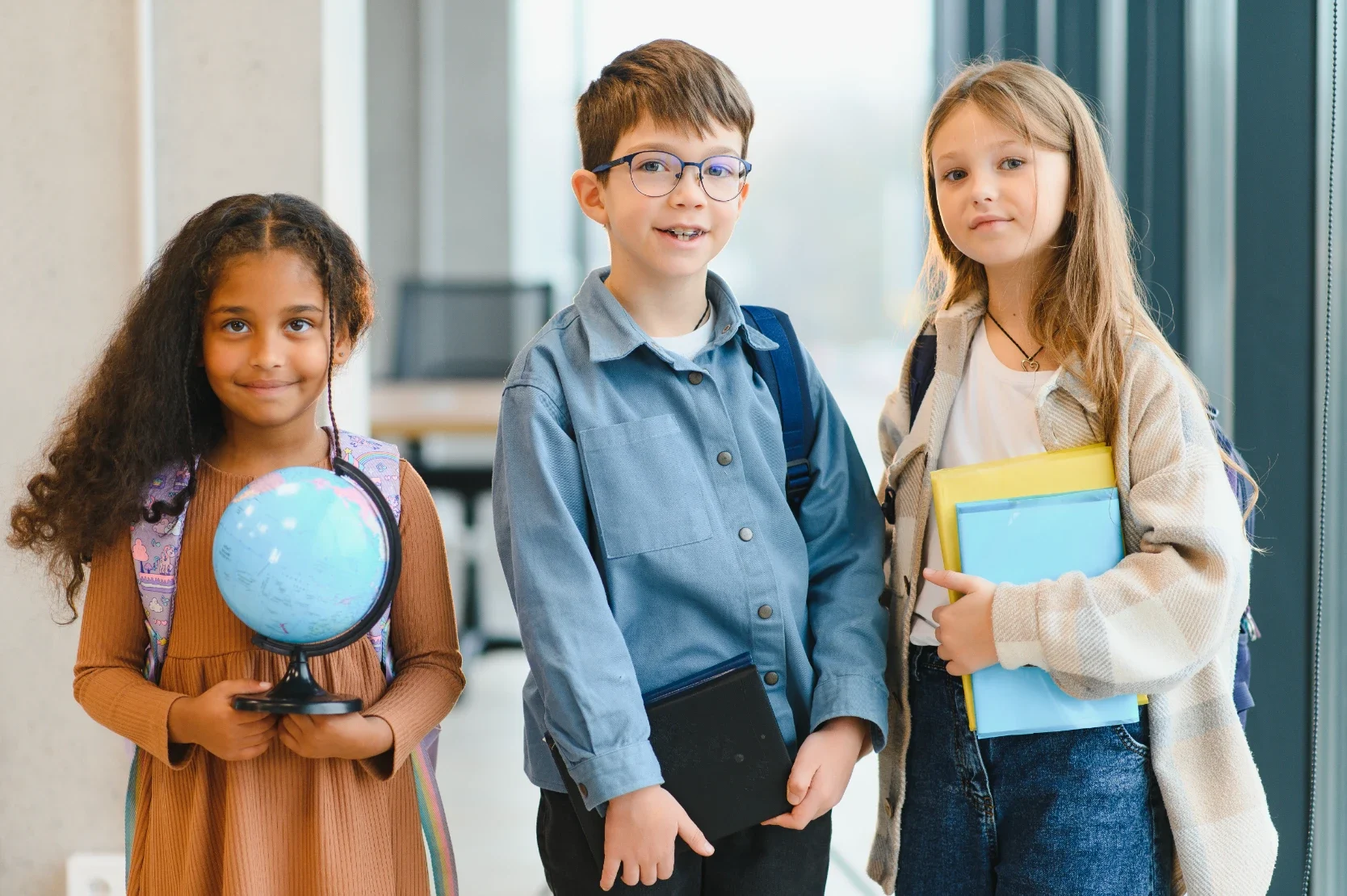 Cheerful Elementary Students Holding School Supplies